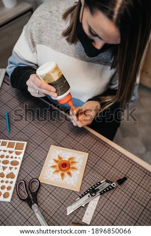 Paper art designer and artist working in her studio or workshop. She is wearing protective face mask against virus pandemic.