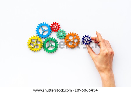 Teamwork concept. Hand connecting gears into puzzle - symbol of working mechanism Royalty-Free Stock Photo #1896866434
