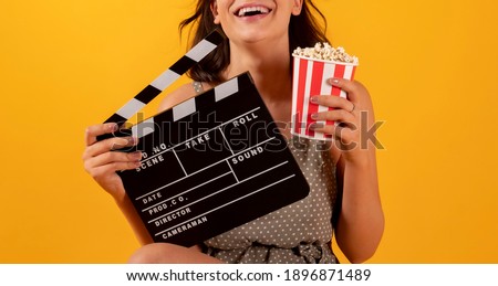 woman with popcorn happy and clapperboard cinema, yellow background