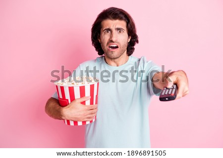 Photo of stressed furious guy hold popcorn switch channel open mouth isolated on pink color background