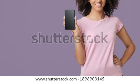 Expert advice, good rating and excellent review. Smiling cute millennial african american female recommended smartphone with blank screen, isolated on purple background, panorama, free space, cropped