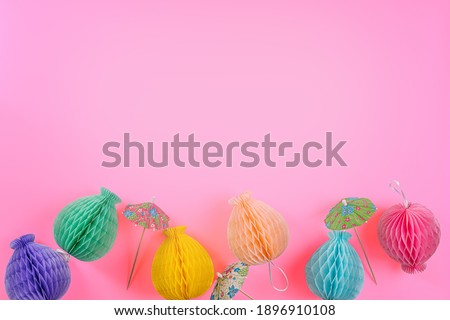 Multicolored paper balls and cocktail umbrella on pink background.Greeting card.Birthday party background.