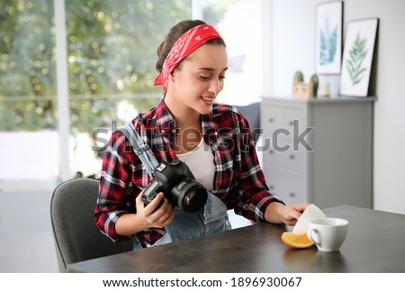 Young photographer taking picture of cups at table indoors