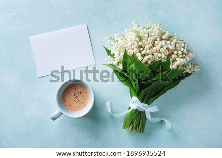 Morning breakfast from fresh coffee cup and spring bouquet of flowers lily of the valley with empty greeting card top view and flat lay.