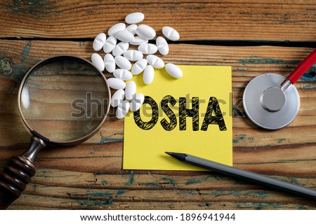 OSHA, Occupational Safety and Health Administration. Magnifying glass on a wooden background