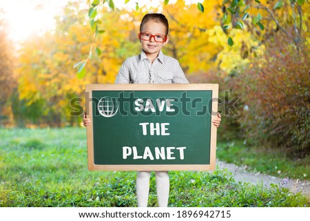 Young girl standing with Save the planet Poster on the backyard.