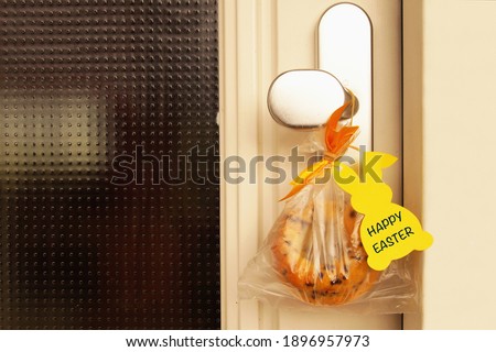 Happy Easter. Easter surprise with handmade cake hanging on door handle with tag, label. Symbol of Easter during the coronavirus pandemic. Safety at Easter quarantine, Covid-19