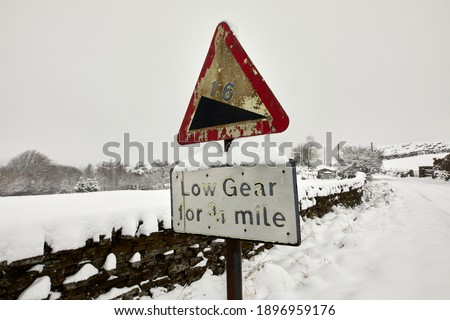 Deep snow after daylong snowfall the warning road sign on moorland single track lane in Nidderdale.