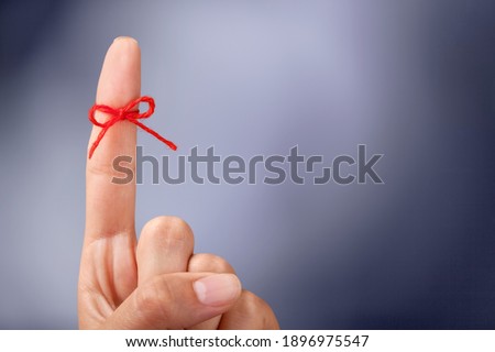 Red thread bow on a human finger Royalty-Free Stock Photo #1896975547