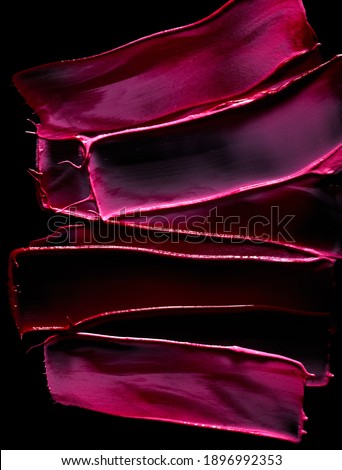 Red and pink lipstick smudges over black background