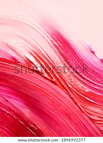 Cosmetic background of smudged lipsticks over light pink background