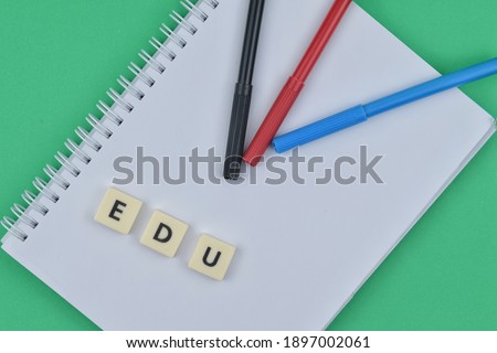 Selective focus image of pen and notebook on green background with edu wording. Business and education concept.