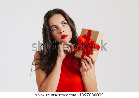Perplexed beautiful brunette girl posing with gift box isolated over white background