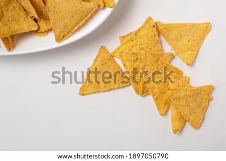 Nachos - appetizer of Mexican cuisine, triangular corn tortilla chips served in white plate on white background, top view Royalty-Free Stock Photo #1897050790