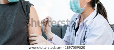Asian professional doctor injecting a Coronavirus 2019-nCoV or COVID-19 vaccine at male patient arm close up, COVID19 vaccinating about protecting and build antibody - immunity against Coronavirus.