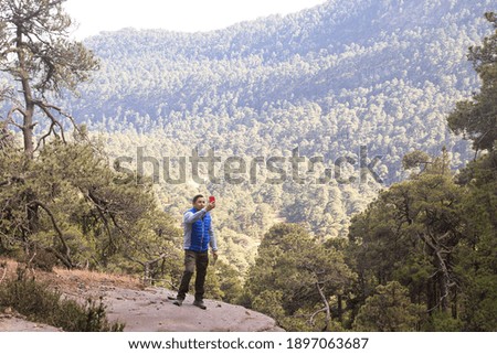 A male hiker standing on rocks on the Iztaccihuatl mountain covered in greenery in Mexico