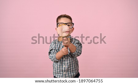 Child looks through a magnifying glass. High quality photo