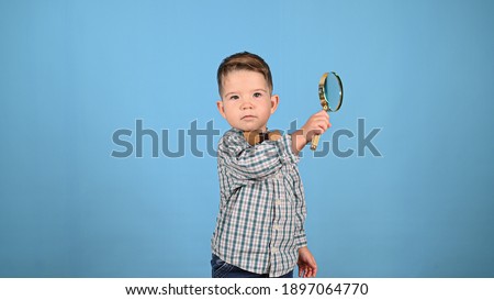 Child and magnifying glass, on a blue background. High quality photo