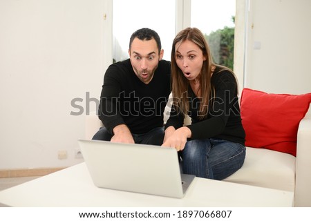 Beautiful couple making shopping internet web browsing search on their computer laptop in the living room