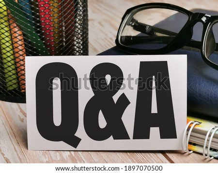 Text Q AND A written on paper note with eye glasses,books and stationary.Business concept.