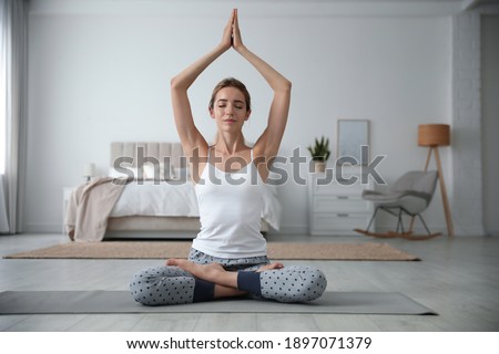 Young woman meditating on floor at home. Morning fitness
