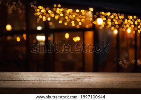 empty wooden table on blurred light gold bokeh of cafe restaurant on dark background, place for your products on the table