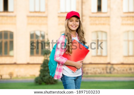 Happy kid in casual fashion style go to school with books carrying backpack outdoors, private lesson.