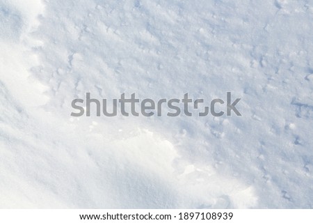 Beautiful winter background with snowy ground. Natural snow texture. Wind sculpted patterns on snow surface. 