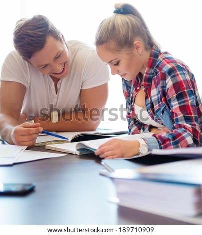 Young students couple preparing for exams behind table 
