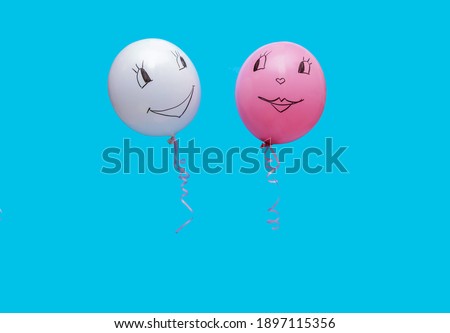 Two balloons on a blue background. A funny face is drawn on the ball.The concept of Valentine's day.