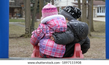 Boy lifting his little sister in snowsuit Royalty-Free Stock Photo #1897115908