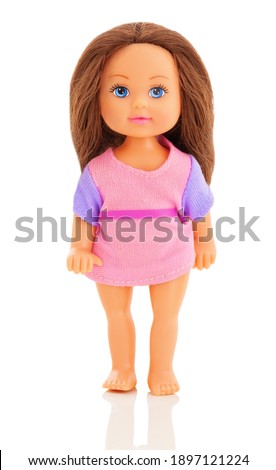 little plastic doll, baby girl. Little brunette doll with blue eyes on white bg. Isolated on white background with shadow reflection. Dressed in a small knitted sweater
