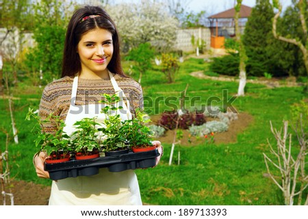 Beautiful smiling woman holding flower plant in garden