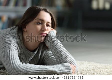 Bored teen looking away lying on the floor at home Royalty-Free Stock Photo #1897134781