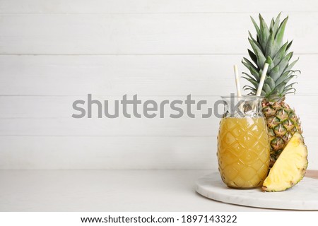 Freshly made pineapple juice on white table. Space for text