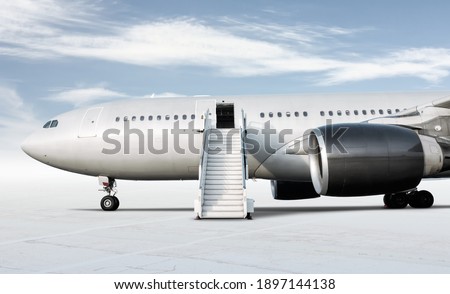 Wide body passenger airplane with a boarding steps at the airport apron isolated on bright background with sky Royalty-Free Stock Photo #1897144138
