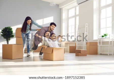 Joyful family with kids having fun in new home. Happy excited first-time buyers with children playing with boxes in the living room. Real estate, residential mortgage, moving into dream house concept Royalty-Free Stock Photo #1897152385