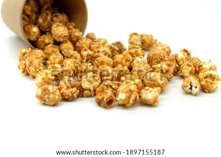 Popcorn with caramel close-up. Popcorn spilled out of a paper cup.  White background.