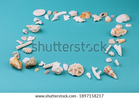 Frame for photo is made from different kinds of seashells, corals in front of a blue background, isolated with a caption for text. Vacation memory concept.