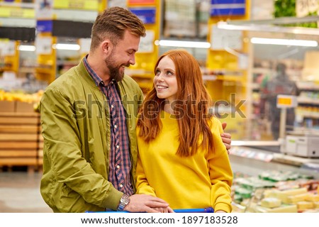couple walk in grocery store choosing food for home, they look at each other with love, smiling
