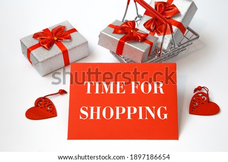 Shopping cart with holiday purchases and text Time for shoppingon a red card, white background.