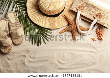 Different beach accessories on sand, flat lay. Space for text