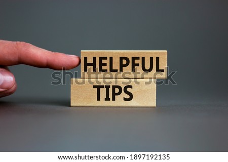Helpful tips symbol. Wooden blocks with words 'Helpful tips'. Beautiful grey background. Businessman hand. Business and helpful tips concept. Copy space.