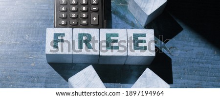 FREE word on wooden cubes with calculator on wooden table background. Business concept.