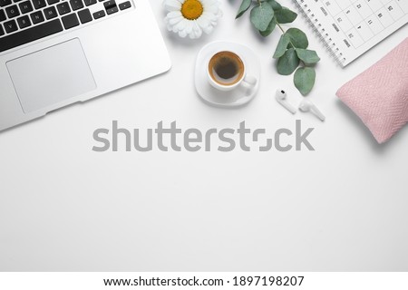 Composition with cup of coffee and laptop on white background, top view