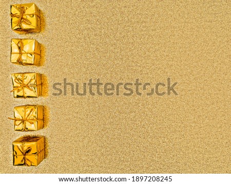 Close-up even row of 5 five gold gift boxes,ropes tied,on left of shiny shimmering golden sequined backdrop,copy space.Concept of holiday,celebration,design of greeting card,banner for discounts,sales