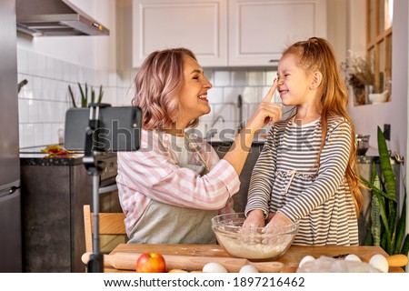 mother food blogger records the process of cooking with daughter on smartphone's camera, they have fun, talk, enjoy preparing food together Royalty-Free Stock Photo #1897216462