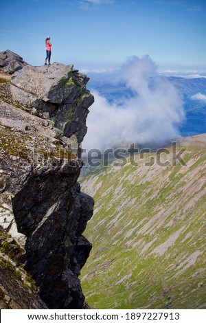 Person standing on cliff edge on Ben Nevis, Scotland. View from the peak of Ben Nevis, sunny day. Royalty-Free Stock Photo #1897227913