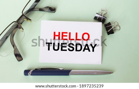 Text Hello Tuesday on business card with eyeglasses and pen. Concept photo