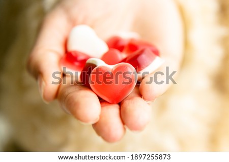 Female hand gives heart shaped jelly gummies